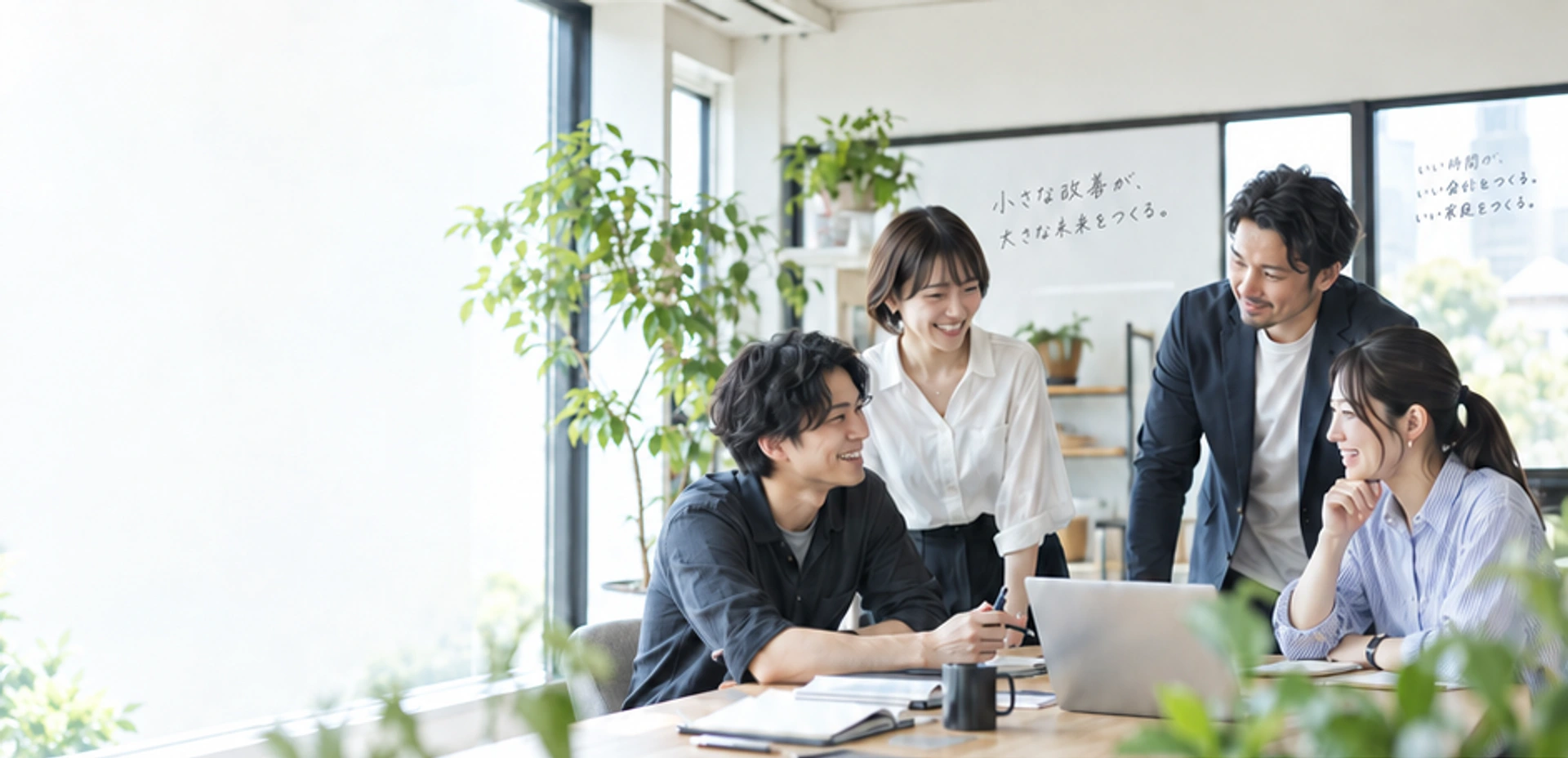 自然光の入るオフィスで、同じテーブルを囲んで対話する人たち